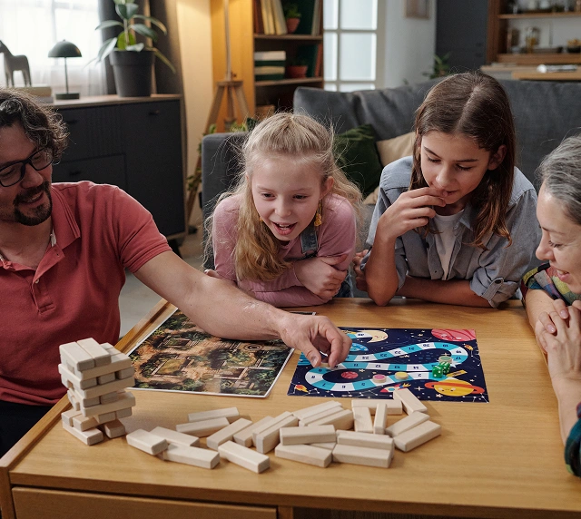 Gezin speelt samen bordspellen thuis, gezellige sfeer met ouders en kinderen die genieten van plezier en interactie rond de tafel.